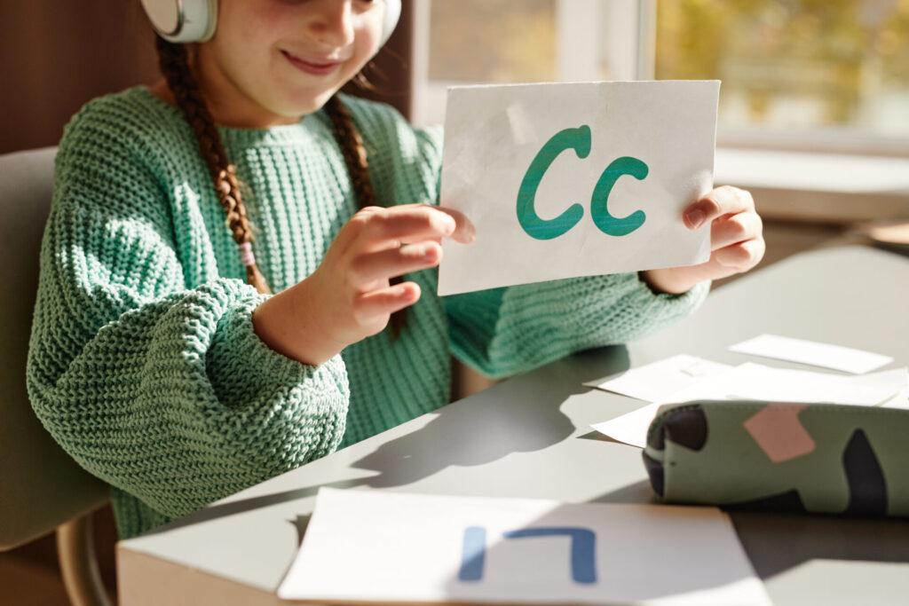 Girl learning English letters at the table
